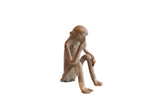 Vintage African sitting monkey figurine in a pensive pose with a rustic, weathered texture.