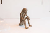 Side view of the vintage African sitting monkey figurine in a pensive pose.