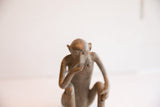 Detailed view of the vintage monkey sculpture's thoughtful face and textured surface.