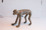 Handcrafted monkey figurine in profile, showing detailed spinal texture and aged patina.