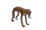 Vintage African monkey figurine with a banana in its mouth, showing a textured, handmade patina.