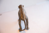 The back of the vintage monkey figurine showing its textured, ridged spine and tail.