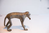 Side profile of a vintage African monkey sculpture showing its elongated form and textured spine.
