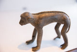 The aged surface and textured spine of the vintage African monkey figurine.