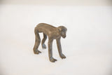 Vintage African monkey figurine with a dark, textured patina, seen from a side profile.