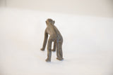 Rear view of a handmade African monkey figurine showing its textured spine and tail.