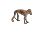 Vintage handmade African monkey sculpture with a weathered, mottled brown patina, shown in profile.