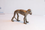 Side profile of a vintage African monkey sculpture showing its weathered, dark patina.
