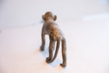 The textured back and long curved tail of the handmade African monkey sculpture.