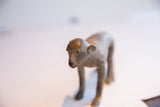 The handmade details and aged patina on the face of a vintage monkey sculpture.