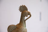 Profile of a vintage African rooster head with a serrated comb, spiral eye, and textured neck.