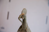 Side profile of the vintage African rooster's head, detailing the textured comb and aged surface.