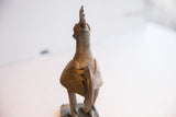 Rear view of a vintage African rooster sculpture, showing the ribbed texture of its long neck and carved back.