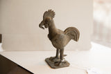Angled profile of the vintage African rooster sculpture, showing its textured wings and tail.