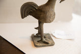 Rear view of a vintage African rooster sculpture showing the layered tail feathers and textured body.