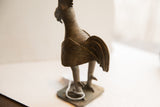 Side view of the vintage African rooster sculpture showing its textured tail and ribbed neck.