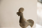Aged bronze African rooster sculpture close-up, highlighting its head, comb, and textured neck.