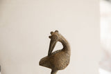 Stylized crest and coiled eye on the textured head of a vintage African bird sculpture.