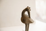 The backward-facing head and textured body of a vintage handmade African bird sculpture.