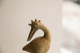 Detail of the crowned head and circular eye on a vintage handmade African bird sculpture.