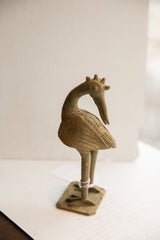 Vintage African bird sculpture in profile, showing its textured surface and unique backwards-facing head.