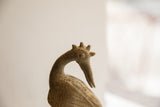 Carved concentric eye and pointed crown on the head of a handmade African bird sculpture.