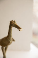 Close-up of the vintage bird sculpture's head showing its stylized eye and the fish in its beak.