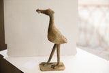 Side profile of the vintage African bird sculpture showing its stylized shape and rustic, textured patina.