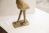A detailed view of the vintage bird sculpture's aged metal legs and feet.