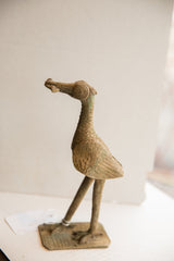 Side view of a handmade African bird sculpture with a rustic, textured patina.