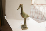Angled view of the vintage African bird sculpture highlighting its handmade texture and form.