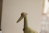 Profile detail of the vintage bird sculpture's head, showing a textured patina and concentric eye.