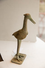 Profile of a vintage African bird sculpture with stippled texture and concentric circle eye.
