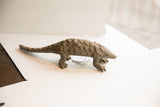 Side profile of a vintage African pangolin sculpture, showing its textured scales and form.