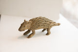 Profile view of a vintage African porcupine sculpture showing its earthen, handmade texture.