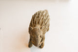 High-angle view of the vintage African porcupine sculpture's face, tusks, and textured back.