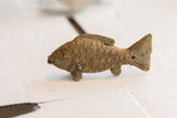 Side view of a vintage African fish figurine with textured scales and weathered patina.