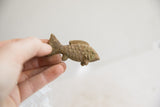 Small vintage African fish figurine with a rustic texture held in hand for scale.
