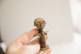 Small African tribal figurine held in hand to show its collectible scale and texture.