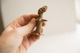 Vintage African woman figurine held in hand to show its petite scale.