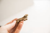 Profile view of a small, rustic African frog sculpture held to show its handmade texture.