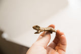 Side profile of a small, handmade African frog figurine showing its rustic texture.