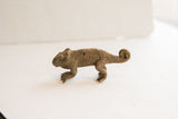 Side profile of a vintage African chameleon figurine showing its textured body and coiled tail.