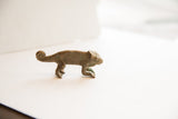 Profile of the vintage African chameleon figurine, detailing its aged texture and curled tail.