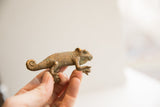 A hand holds the vintage chameleon figurine, highlighting its textured bronze patina.