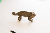 Side view of the vintage African chameleon sculpture highlighting its textured body and curled tail.