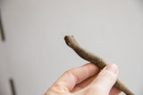 The simple, hand-carved head and rough, earthy texture of a vintage snake figurine.