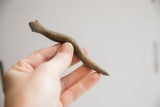 A vintage African snake figurine held to show its slender form and rustic texture.
