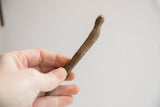 Vintage African snake figurine held in hand, showing its slender scale and texture.