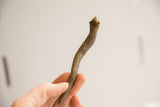 Vintage snake figurine held to show its handmade, rustic texture and small scale.